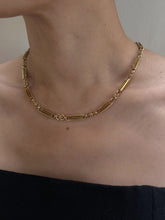 Load image into Gallery viewer, Close-up of a person's neck adorned with the "Antique 15K Gold Chain with 15K Hook and Split Ring c.1860-70," featuring a combination of rectangular and small circular links that evoke the charm of an antique English watch chain. The individual is dressed in a strapless black top against a neutral background, highlighting the necklace's minimalist and elegant design.