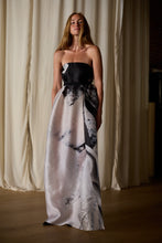 Load image into Gallery viewer, A woman stands in front of cream-colored curtains while modeling the Custom Shuimo Painting Dress | Satin Organza Buckhouse Print. The custom-made dress features an exclusive print with abstract black and gray patterns and a fitted bodice. She has long, straight hair, and her hands are at her sides.