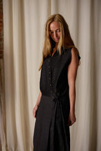 Load image into Gallery viewer, A person with long blonde hair stands against a backdrop of light-colored curtains, wearing a Xiang Yun Silk Wrap Dress. Crafted from Xiang Yun Silk, the handmade in-house dress complements their calm expression as they gaze down thoughtfully.