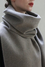 Load image into Gallery viewer, A close-up of a person wearing a Long Scarf Double-face Cashmere | Undyed Natural that wraps around their neck and shoulders. The handmade scarf appears thick and cozy, partially covering the person's mouth. They have fair skin and are wearing red lipstick.