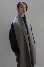 Load image into Gallery viewer, A person with straight dark hair is wearing a dark long-sleeve shirt, brown pants, and a Long Scarf Double-face Cashmere | Undyed Natural draped over their shoulders. They are standing against a plain, light-colored background, looking slightly to the side.
