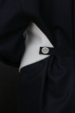 Load image into Gallery viewer, Close-up of a garment featuring black and white fabric. The image highlights a ceramic button on a black strap over the white section, contrasting with the black main material. The design suggests attention to detail and fabric interplay, utilizing zero waste design principles. This is the X Scarf - Double-face Cashmere | Undyed.