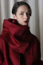 Load image into Gallery viewer, A person with short hair is wearing a rich wine X Scarf, made of double-faced cashmere, featuring a large collar partially covering their neck. They have a neutral expression and stand against a softly lit, neutral background.