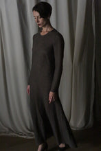Load image into Gallery viewer, A woman with short dark hair stands indoors, wearing the Long Sleeved Crewneck Dress in dark brown wool gauze. She gazes downward calmly, framed by softly draped beige curtains—handmade in San Francisco.