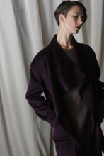 Load image into Gallery viewer, A person with short hair poses elegantly against a white curtain in an aubergine Winston Long Double-face coat. The luxurious double-faced cashmere garment offers versatile styling options as they gaze thoughtfully to the side.