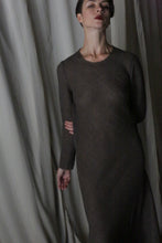 Load image into Gallery viewer, A woman with short dark hair and a neutral expression poses in front of draped white fabric, wearing the Long Sleeved Crewneck Dress—an elegant handmade design from San Francisco. One arm is bent behind her back.