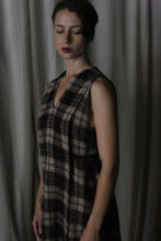 Load image into Gallery viewer, A woman with short dark hair, eyes closed, wears The Winter Dress in Japanese Wool Gauze Taupe Plaid, standing against a softly lit, neutral curtain backdrop.