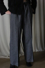 Load image into Gallery viewer, Wearing Brushed Cotton Trousers in Blue Herringbone, a person with a dark top stands against curtains. Hands in pockets, dim lighting casts shadows.