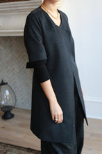 Load image into Gallery viewer, A person in a dark double-breasted Wexley coat over a black long-sleeve shirt, wearing a gold necklace and a ring on their left hand, stands on parquet flooring beside a decorative lantern. Their face is not visible.