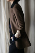 A person wearing a Sloane | Taupe / Black equestrian length cashmere blazer with a folded cuff over a black collared shirt and black trousers.