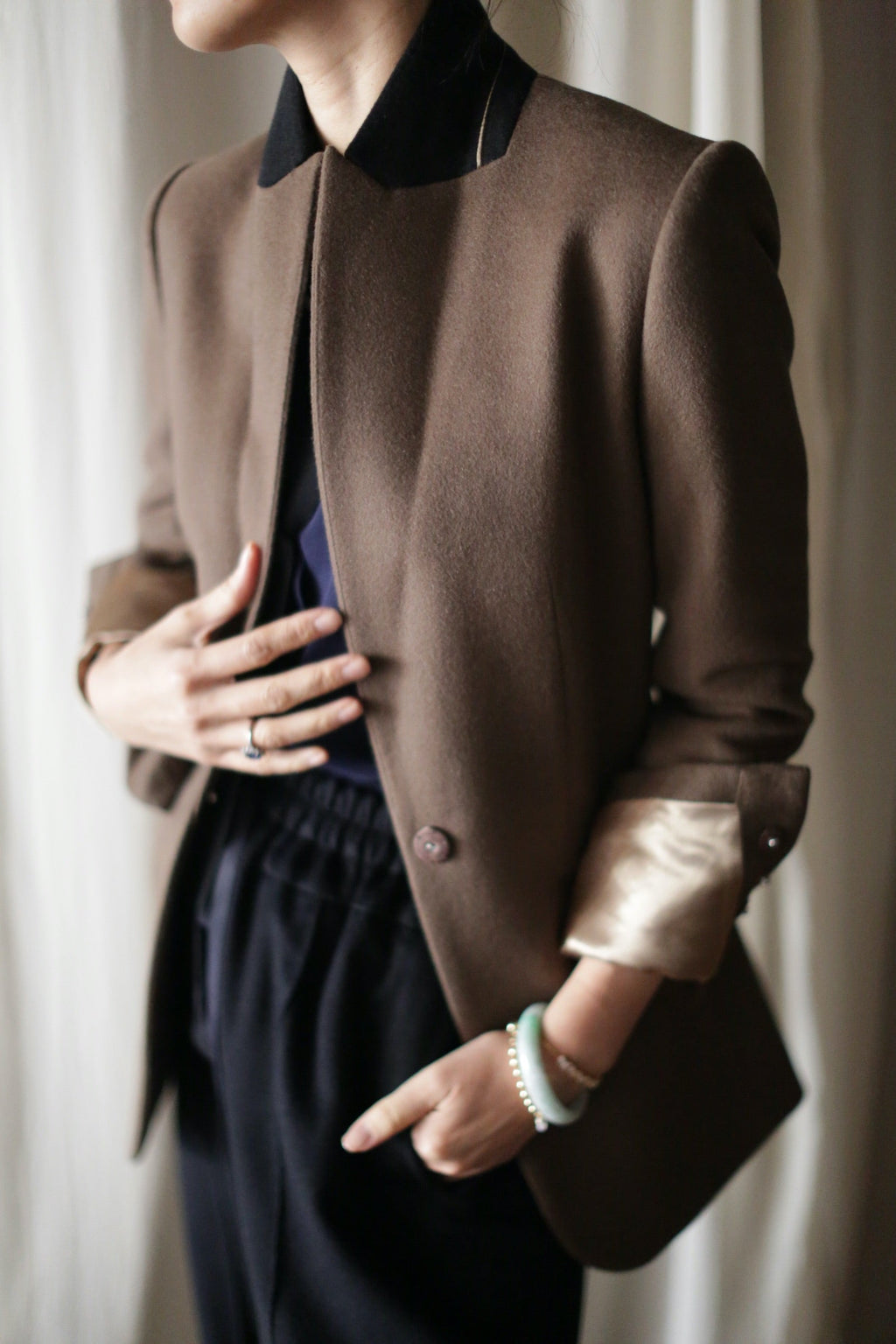 A person wearing the Sloane | Taupe / Black equestrian length blazer with a black collar over a dark shirt and pants.