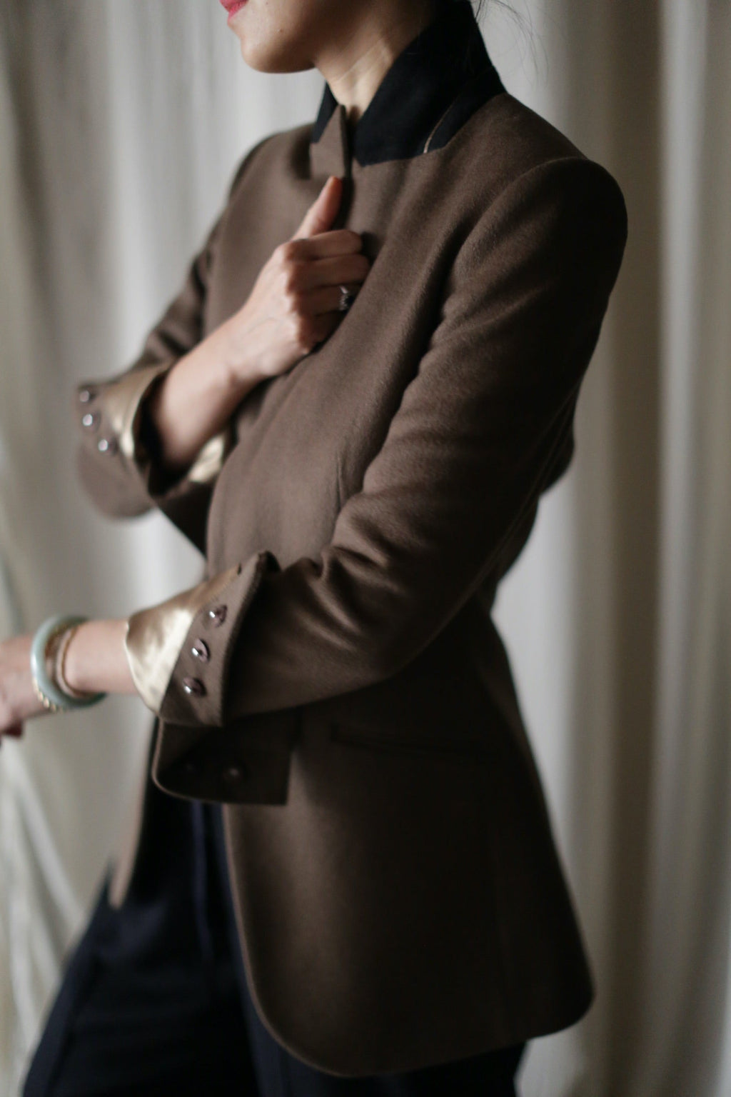A person wearing the Sloane | Taupe / Black equestrian-length blazer, featuring a high black collar and folded cuffs with a metallic lining.