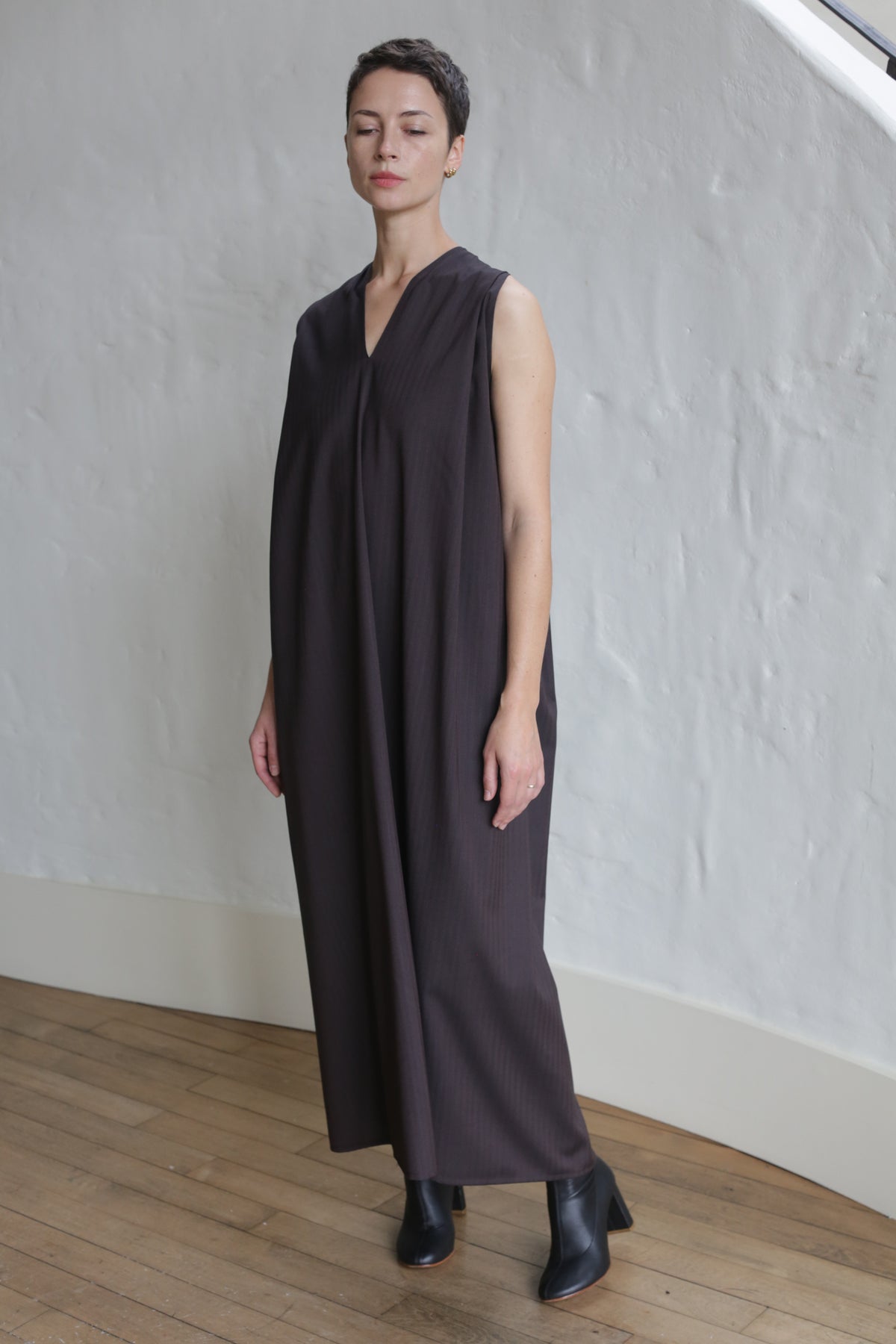 A woman wearing the Belted Dress in wool herringbone brown.
