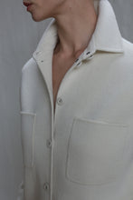 Load image into Gallery viewer, A person wears the Studio Shirt | Undyed—an off-white, button-up fleece jacket with large chest pockets and a turned-up collar—shown from shoulders to just below the chin against a neutral background.