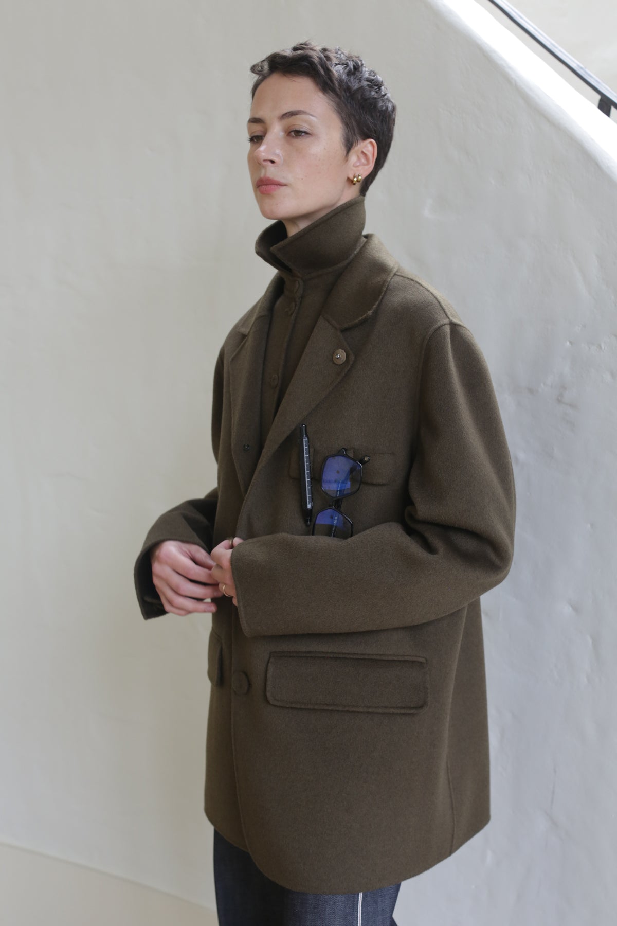 A woman wearing the Sculptor's Jacket in Olive.