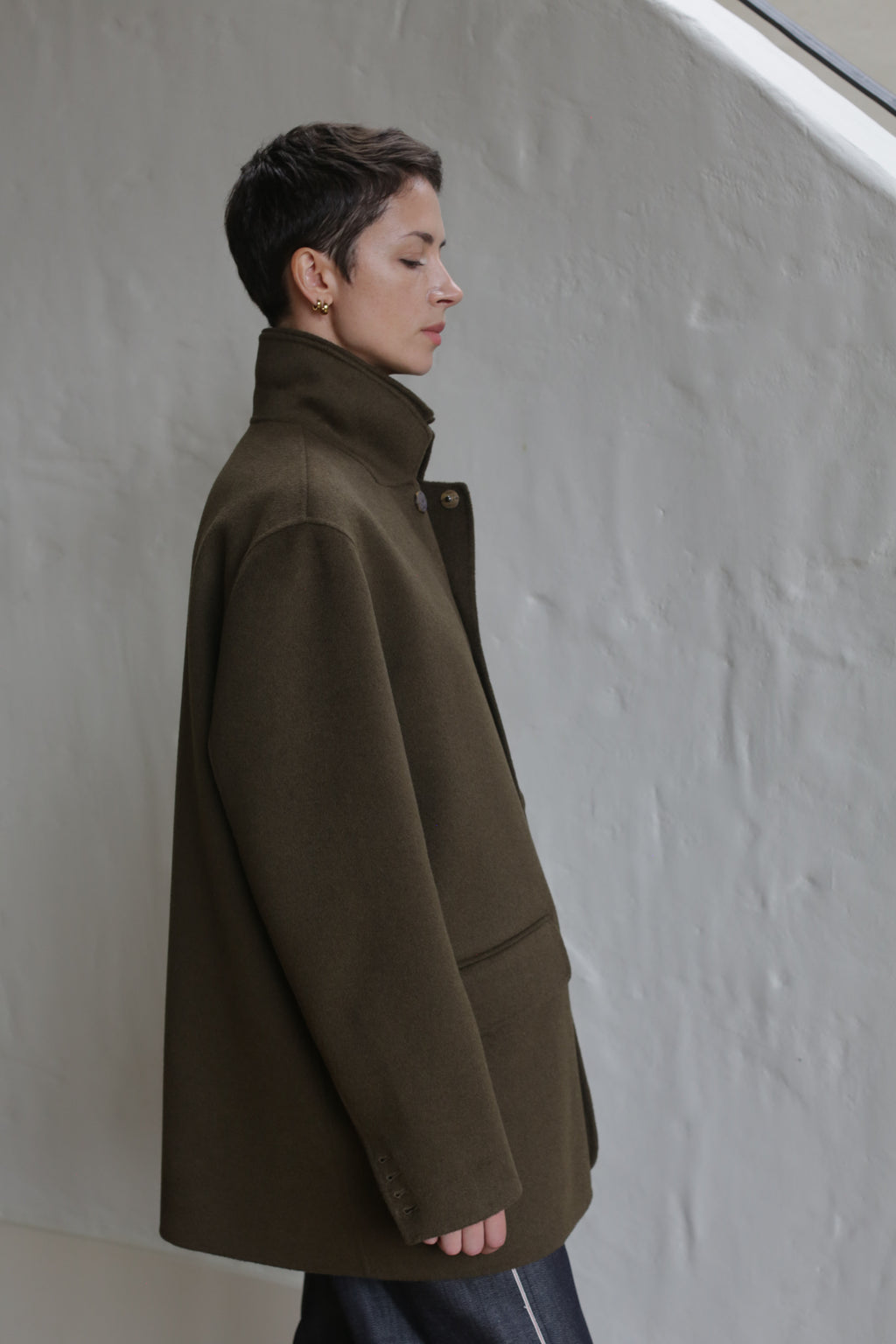 A woman wearing the Sculptor's Jacket in Olive.