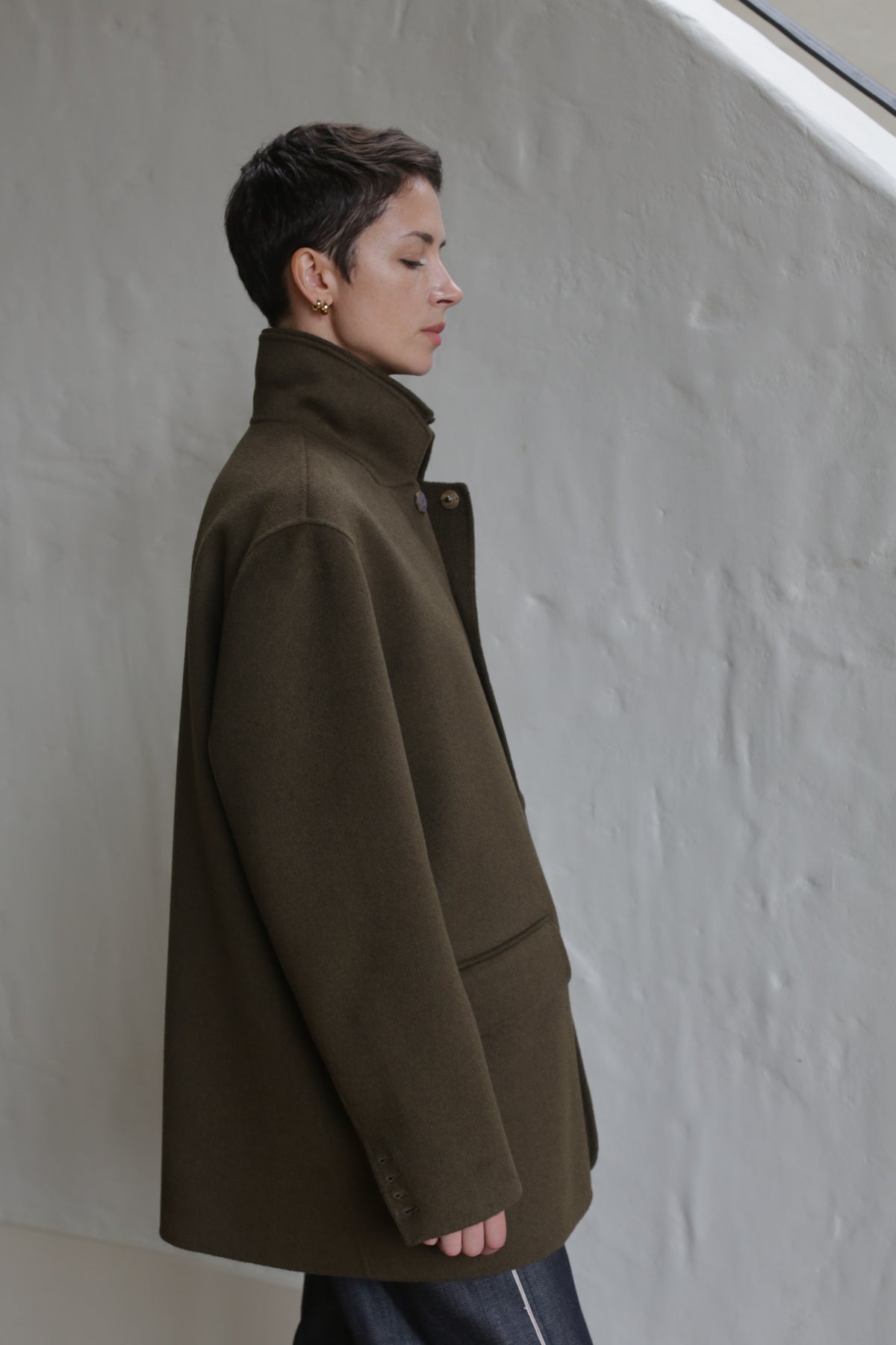 A woman wearing the Sculptor's Jacket in Olive.