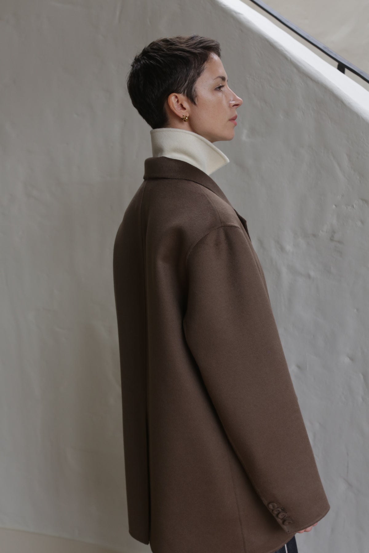 A woman wears the Sculptor's Jacket in taupe.