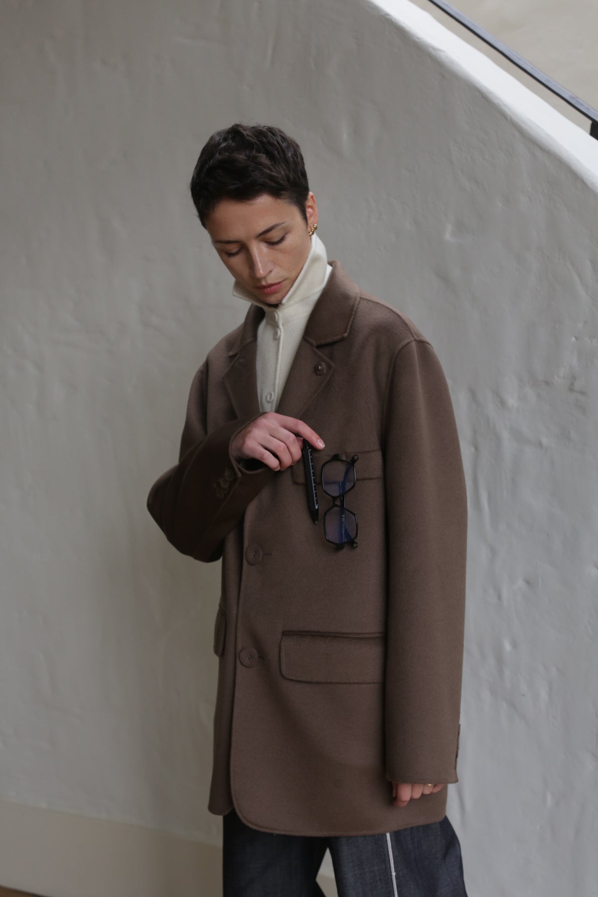 A person wearing the Sculptor's Jacket in Taupe with glasses in their pocket.
