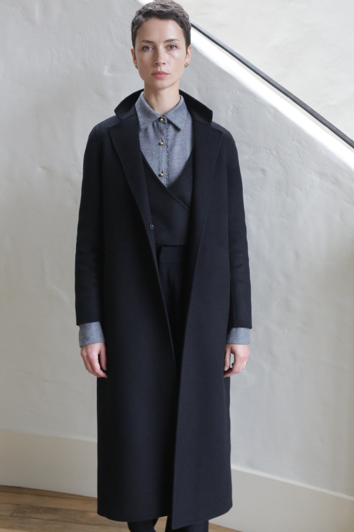 A woman wears the X-Scarf Coat in Watermark Black.