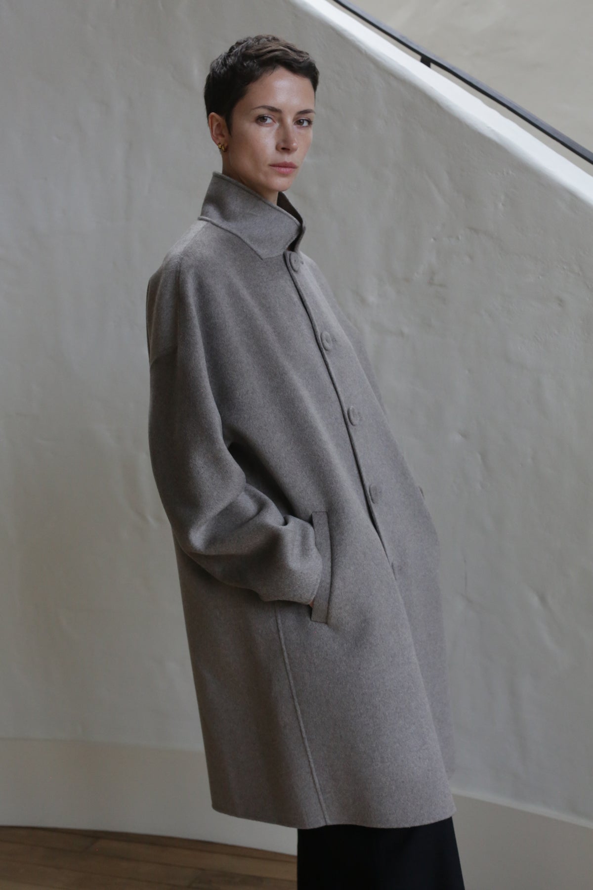A man wears the Men's Coat in Undyed Natural.