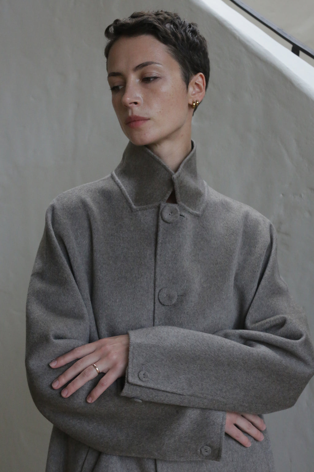 A person with short hair wearing the Men's Coat in Undyed Natural.