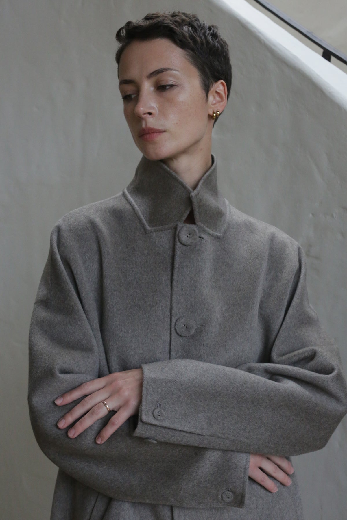 A person with short hair wearing the Men's Coat in Undyed Natural.