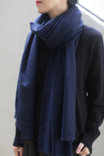 Load image into Gallery viewer, A person is wearing a Tissue Weight Cashmere Scarf in navy, draped around their neck over a black sweater. The person has their head turned slightly to the side, with only their lower face visible, showing red lipstick. The background is neutral and out of focus.