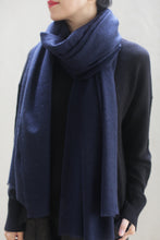 Load image into Gallery viewer, A person wearing a dark blue Tissue Weight Cashmere Scarf in Navy and a black sweater. Only the lower half of their face and upper torso are visible against a light-colored background. Their dark hair is pulled back, and their arms are relaxed by their sides.