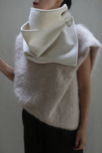 Load image into Gallery viewer, A person is stylishly draped in the Wrap Scarf | Undyed, a luxurious, soft accessory made from fur-like double-face cashmere in a delicate light beige hue. The large, off-white cowl-like collar elegantly folds over and fastens with buttons at the top, showcasing an exquisite design that adheres to zero waste principles. The ensemble exudes sophistication against the plain light gray backdrop.