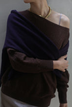 Load image into Gallery viewer, A person with short hair dons the Ballerina&#39;s Cashmere Sweater in Chestnut, exuding cozy elegance as a true wardrobe staple, paired with a dark scarf draped over their shoulders. The sweater is casually styled to let one shoulder slip slightly off, revealing a delicate strap beneath. A gold necklace adds a touch of shine around the neck as they stand against a neutral background.