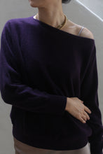 Load image into Gallery viewer, A person wearing the Aubergine Ballerina&#39;s Cashmere Sweater and a pearl necklace stands against a light background, with one hand resting on their hip.