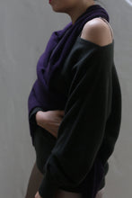 Load image into Gallery viewer, A person is seen wearing a dark olive, off-shoulder cashmere sweater—an essential wardrobe staple—complemented by a purple scarf. Positioned in profile with their hand gently resting on their abdomen, the minimalist neutral background enhances the introspective atmosphere.