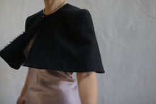 Load image into Gallery viewer, A person wearing a silky light pink dress and a Capelet made from Japanese Wool Gauze in black stands against a plain, light gray background. The individual&#39;s face is not visible, and they have a gold chain necklace around their neck. This outfit can be custom ordered with a short lead time for personal tailoring.