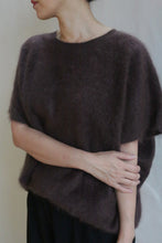 Load image into Gallery viewer, A person wearing the Salento | Mink loose, short-sleeved brushed cashmere sweater holds their left arm with their right hand and faces slightly away from the camera against a plain background.