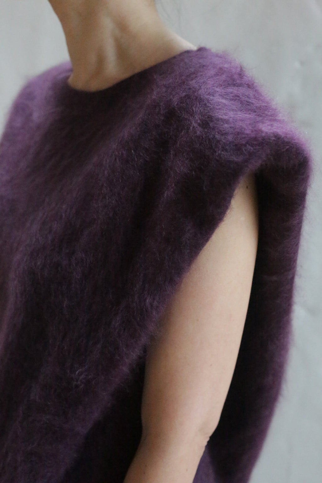 A person models the Salento | Aubergine sleeveless brushed cashmere top against a neutral background, with only their upper torso, shoulder, neck, and part of the arm visible.