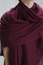 Load image into Gallery viewer, A person drapes the Tissue Weight Cashmere Scarf in Garnet, sized 36&quot; x 82&quot;, around their shoulders with layered folds, showing only their lower face, neckline, and upper torso.