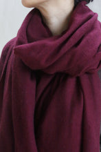 Load image into Gallery viewer, A person with short dark hair wears the Tissue Weight Cashmere Scarf in Garnet, wrapped snugly around their neck and shoulders. Only the lower half of their face and part of their upper torso are visible.