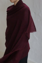 Load image into Gallery viewer, A person drapes the Tissue Weight Cashmere Scarf in Garnet over their shoulders, standing against a plain light background with their face partially out of view.