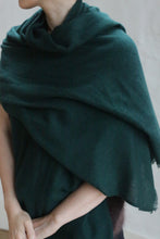 Load image into Gallery viewer, A person stands with their hands clasped, draped in the Tissue Weight Cashmere Scarf in Forest (36 x 82 inches), facing slightly left. Their face is partially out of frame.