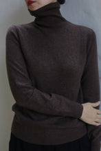 Load image into Gallery viewer, A person wears the Cashmere Turtleneck | Coffee, standing against a light-colored wall with one arm crossed and red lipstick partially visible.