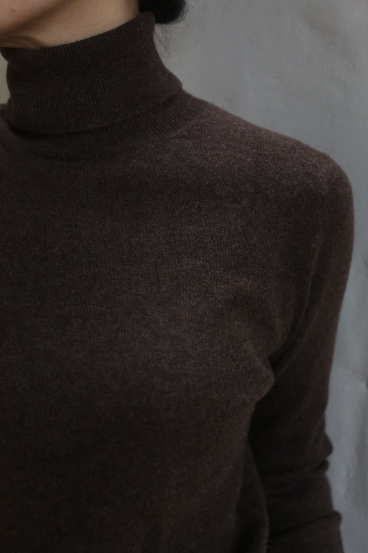 A person wearing the Coffee Cashmere Turtleneck, with only their lower face and upper torso visible, stands against a plain light gray background.
