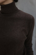 Load image into Gallery viewer, A person wearing the Coffee Cashmere Turtleneck, with only their lower face and upper torso visible, stands against a plain light gray background.