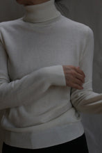 Load image into Gallery viewer, A person models the Cashmere Turtleneck in Ivory, standing against a neutral background with arms crossed at the waist and head partially out of frame.