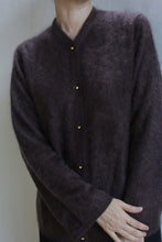 Load image into Gallery viewer, A person wears the Brushed Cashmere Cardigan in Mink, featuring brass buttons. They stand against a plain light background with arms crossed at the wrists and head slightly tilted down, partially out of frame.