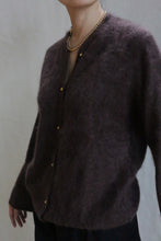 Load image into Gallery viewer, A person wears the Brushed Cashmere Cardigan | Mink—dark brown and fuzzy with brass buttons—and a gold beaded necklace, standing against a plain light background. Their head is partially out of frame.