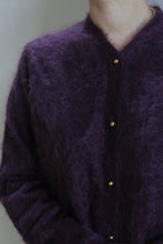 Load image into Gallery viewer, A person is shown from neck to waist wearing the Brushed Cashmere Cardigan in Aubergine, featuring gold buttons. The background is plain and the face is not visible, highlighting this luxury knitwear piece.