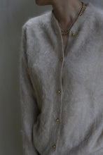 Load image into Gallery viewer, A person wearing a soft Brushed Cashmere Cardigan in Sandstone with gold buttons and layered gold necklaces; only the upper torso and part of the neck are visible.