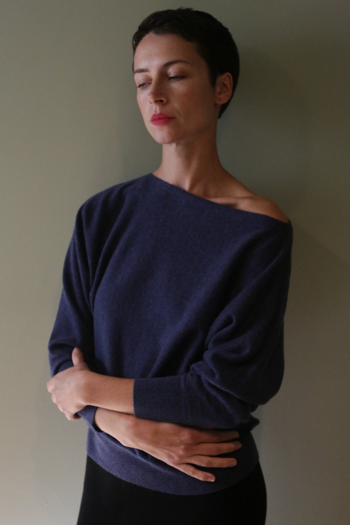 A person wearing a Ballerina’s Cashmere Sweater | Navy, an off-the-shoulder long-sleeved cashmere sweater with a relaxed silhouette.
