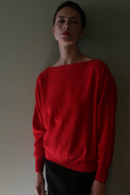 Load image into Gallery viewer, A person wearing a bright red Ballerina’s Cashmere Sweater | Vermillion with a relaxed silhouette and a wide boat neckline.